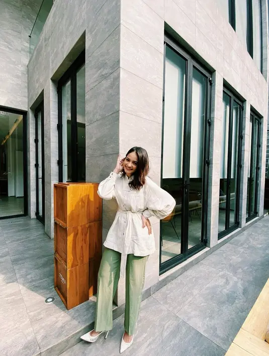 Kemeja oversize berwarna broken white dengan detail ikat pinggang dipadu padankan dengan celana berwarna hijau adalah outfit yang comfy dan lucu untuk ke kantor. (instagram/enzystoria)