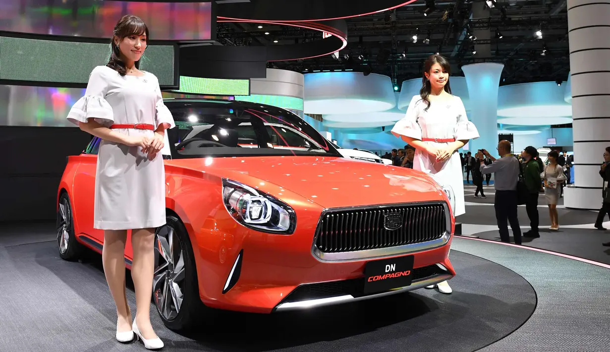 Dua model berpose di dekat mobil Daihatsu DN Compagno selama Tokyo Motor Show di Tokyo, Jepang (25/10). Pameran ini digelar dari 25 Oktober sampai 5 November 2017. (AFP Photo/Toshifumi Kitamura)