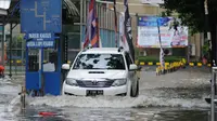 Sebuah mobil menerobos genangan air di depan kampus UKRIDA, Jakarta, Selasa (21/1). Hujan deras sejak malam tadi, membuat sejumlah wilayah Jakarta tergenang air banjir. (Liputan6.com/Gempur M Surya)