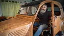 Seorang pensiunan tukang lemari, Michael Robillard, duduk di replika mobil legendaris Citroen 2CV dari kayu di bengkel kerjanya di Loches, Prancis, 21 Maret 2017. Mobil klasik itu dibuat dengan skala sesungguhnya atau 1:1. (GUILLAUME SOUVANT/AFP)