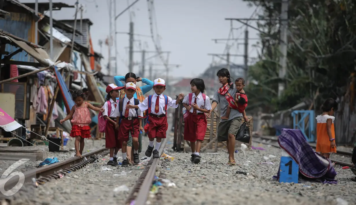 Sejumlah siswa siswi SD melintas di rel kereta di kawasan Kampung bandan, Jakarta, Selasa (28/7/2015).  Pemprov DKI Jakarta berencana menata sekitar Stasiun dengan membangun rumah susun yang memanfaatkan lahan milik PT KAI. (Liputan6.com/Faizal Fanani)