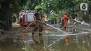 Petugas pemadam kebakaran menyemprotkan air untuk membersihkan lumpur sisa banjir di Kawasan Bukit Duri, Jakarta, Sabtu (4/1/2020). Meski banjir sudah mulai surut, jalan-jalan dan permukiman warga masih tertutup lumpur tebal. (merdeka.com/Imam Buhori)