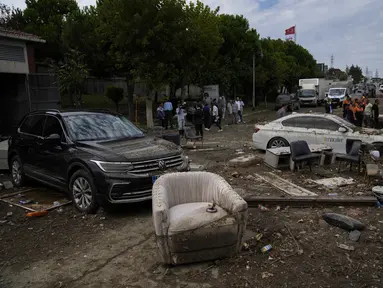 Orang-orang berjalan di samping kendaraan dan perabotan yang berserakan pasca banjir akibat hujan lebat di Istanbul, Turki, RBu (6/9/2023). (AP Photo/Khalil Hamra)