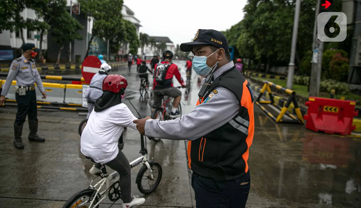 Petugas Dishub mengatur pesepeda saat uji coba penerapan zona rendah emisi di Kota Tua, Jakarta, Minggu (20/12/2020). Selama penerapan zona rendah emisi, kawasan Kota Tua hanya bisa dilalui pejalan kaki, pesepeda, angkutan umum, dan kendaraan khusus yang lulus uji emisi. (Liputan6.com/Faizal Fanani)