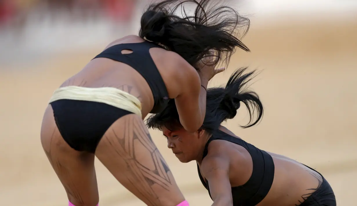 Dua wanita adat sedang bergulat dalam pertandingan yang disebut Huka Huka pada Olimpiade bagi Masyarakat adat, Palmas, Brasil, (30/10/2015). Masyarakat adat dari 22 negara di dunia ikut memeriahkan acara ini. (REUTERS/Ueslei Marcelino)