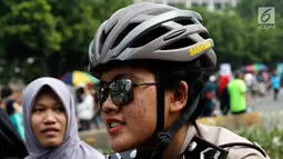 Seorang polisi wanita mengenakan helm dan kacamata berpatroli dengan sepeda di lokasi car free day, Jakarta, Minggu (21/5). (Liputan6.com/Immanuel Antonius)