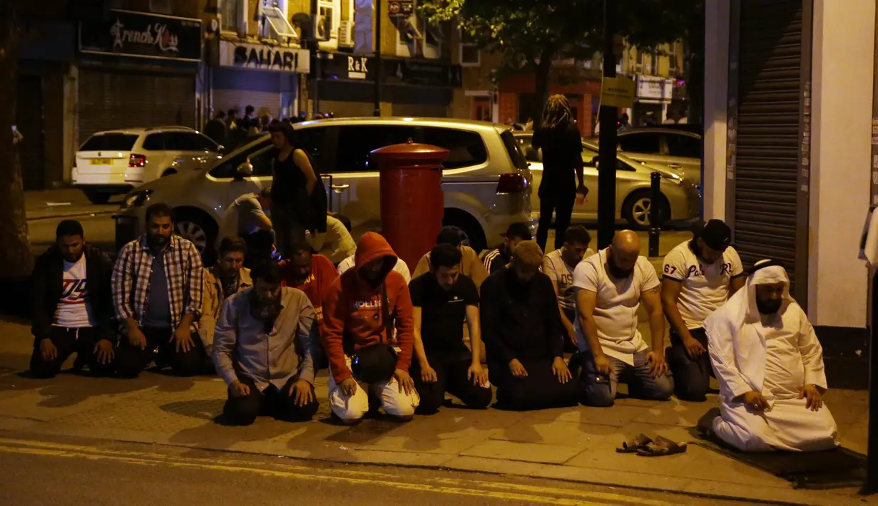Umat muslim melaksanakan salat di lokasi sebuah van yang menabrak pejalan kaki di Finsbury Park Road, London utara, Senin (19/6). Kepolisian Metropolitan meyakinkan sopir mobil van tersebut telah ditahan. (DANIEL LEAL-OLIVAS / AFP)