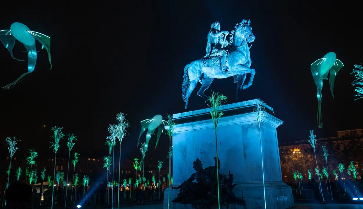 Patung Louis XIV di Bellecour Place diterangi cahaya lampu selama Festival of Lights (Fete des Lumieres) di kota Lyon, Prancis, Kamis (5/12/2019). Festival yang digelar sejak tahun 1852 ini berlangsung, bertepatan dengan musim liburan Natal. (ROMAIN LAFABREGUE / AFP)