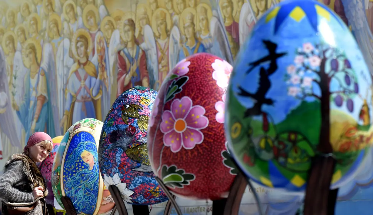 Seorang wanita melihat telur Paskah besar yang dipajang di depan Katedral Mikhaylivsky di pusat Kiev sebelum perayaan Paskah, Ukraina, Rabu (12/4). Keberadaan telur Paskah besar ini menjadi daya tarik bagi wisatawan. (AFP PHOTO / Sergei SUPINSKY)