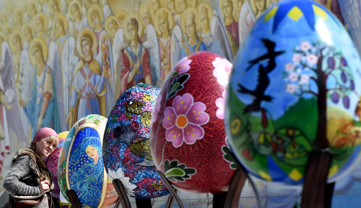 Seorang wanita melihat telur Paskah besar yang dipajang di depan Katedral Mikhaylivsky di pusat Kiev sebelum perayaan Paskah, Ukraina, Rabu (12/4). Keberadaan telur Paskah besar ini menjadi daya tarik bagi wisatawan. (AFP PHOTO / Sergei SUPINSKY)