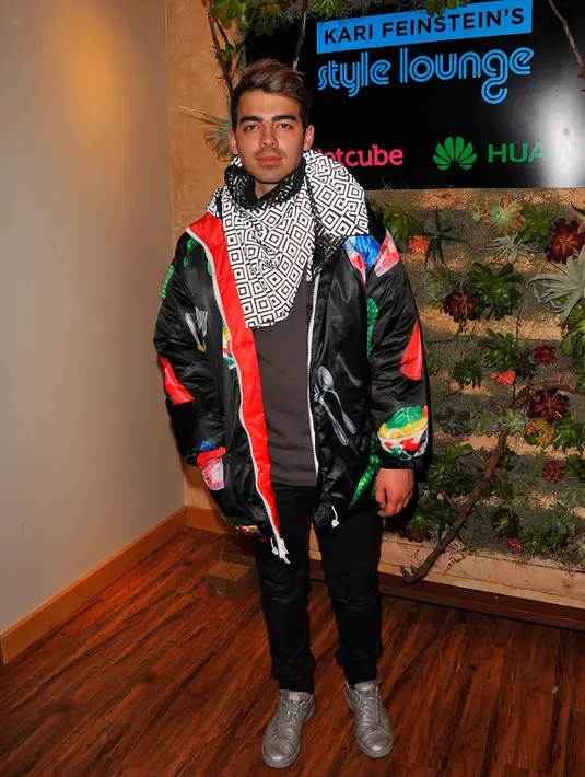 Joe Jonas mengenakan jaket hitam berdesain unik saat acara Kari Feinstein's Style Lounge di Utah, 23 Januari 2016. Di bagian lain jaket itu, ada gambar botol saus, pete hingga pecahan uang Indonesia. (Lily Lawrence/Getty Images untuk Kari Feinstein/AFP)