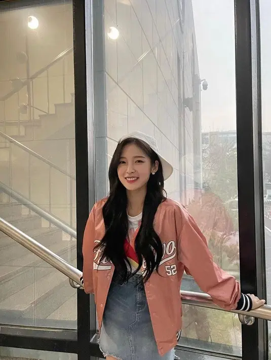 Kombinasi baseball jacket warna peach dengan t-shirt dan denim skirt juga tak kalah menarik, seperti yang dikenakan Arin Oh My Girl. (Instagram/ye._.vely618).