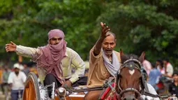 Peserta membalap kereta kuda mereka selama perlombaan tradisional yang diadakan setiap hari Senin bulan kalender Hindu Saawan di Prayagraj, India, Senin (13/7/2020). Bulan Saawan, bertepatan dengan musim hujan. (AP Photo/Rajesh Kumar Singh)