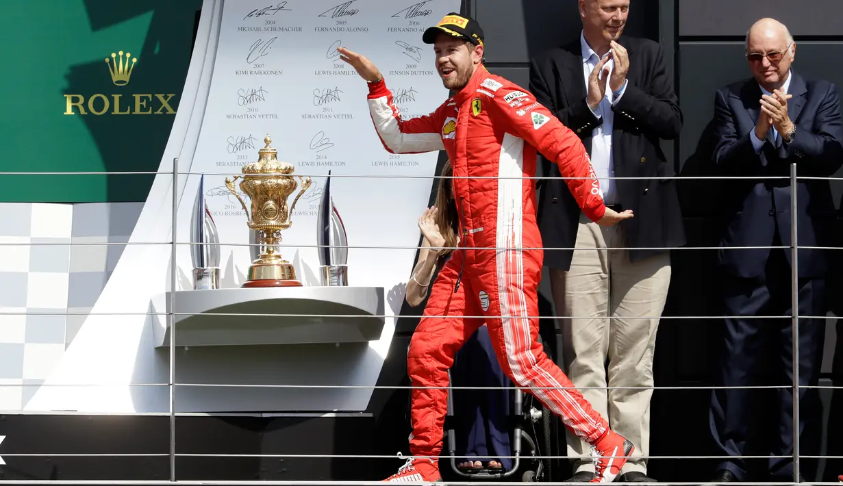 Gaya pembalap Ferrari, Sebastian Vettel saat menaiki podium setelah memenangkan F1 GP di Sirkuit Silverstone, Inggris, Minggu (8/7). Vettel mengungguli Lewis Hamilton dan Kimi Raikkonen. (AP Photo/Luca Bruno)