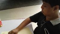 Bayu Yulianto sedang membaca dan menulis dengan huruf braille. (Foto: Giovani Dio Prasasti)