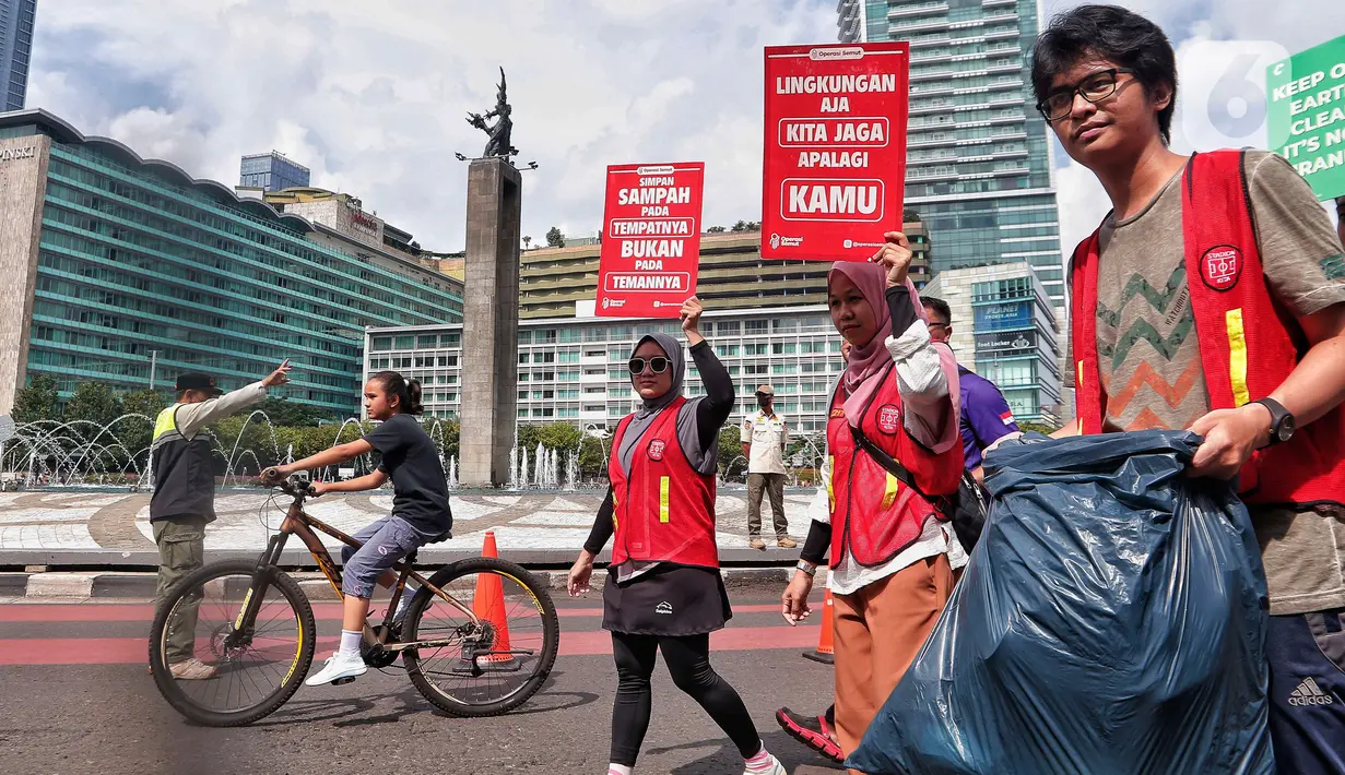 Relawan 'Operasi Semut' dari berbagai komunitas mengajak para pengunjung CFD untuk memungut sampah di Kawasan Bundaran HI, Jakarta, Minggu (19/2/2023). Aksi memungut sampah tersebut merupakan kampanye memperingati 'Hari Peduli Sampah Nasional dan Hari Bersih Indonesia 2023'. (Liputan6.com/Angga Yuniar)