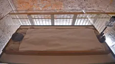 Mumi yang terbungkus linen dari dinasti ke-18 Firaun Tutankhamun (1332–1323 SM) terlihat dalam kotak kaca di makam bawah tanah (KV62) di Lembah Para Raja di tepi barat sungai Nil di seberang kota Luxor di Mesir (31/1). (AFP Photo/Mohamed El-Shahed)