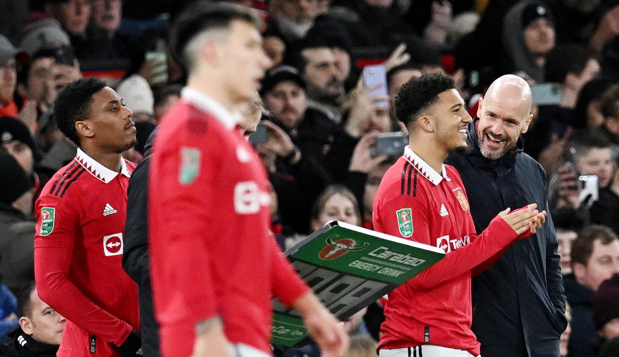Pelatih Manchester United, Erik ten Hag, berbincang dengan Jadon Sancho saat melawan Nottingham Forest pada leg kedua babak semifinal Carabao Cup, di Stadion Old Trafford, Jumat (2/2/2023). Jadon Sancho kembali bermain untuk Manchester United setelah cukup lama hilang. (AFP/Paul Ellis)