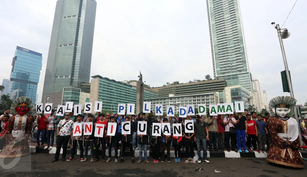 Sejumlah orang yang tergabung dalam Koalisi Pilkada Damai Tanpa Kecurangan (KPD-TK) memegang tulisan Pilkada Damai Anti Curang di kawasan hari bebas kendaraan di Bundaran HI, Jakarta, Minggu (2/4). (Liputan6.com/Johan Tallo)