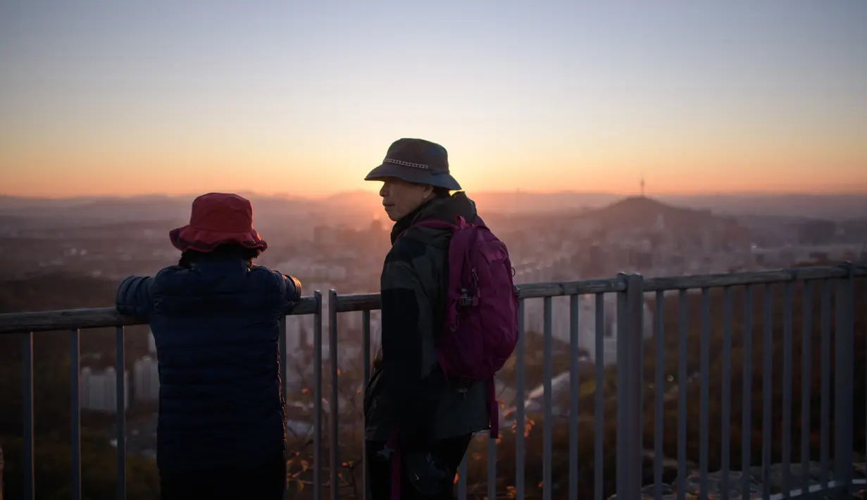 Pejalan kaki menikmati keindahan kota Seoul dan menara Namsan selama matahari terbit di Korea Selatan (31/10). Seoul adalah ibu kota Korea Selatan yang berusia lebih dari 600 tahun. (AFP Photo/Ed Jones)