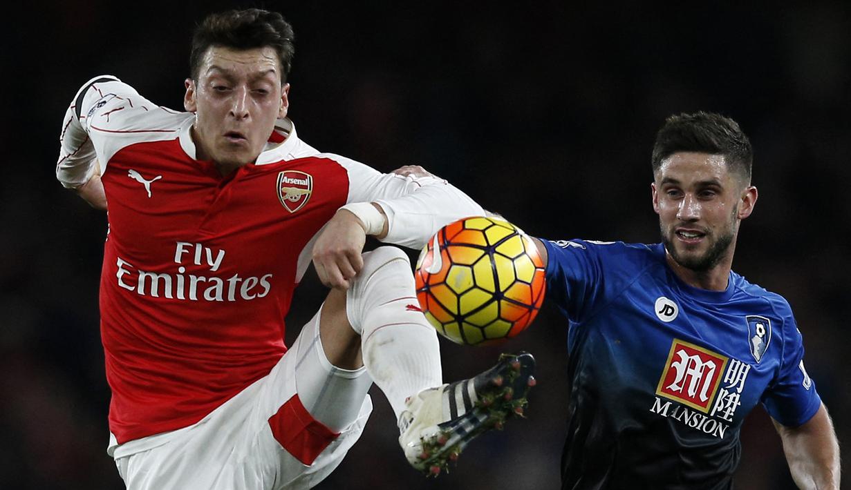 Gelandang Arsenal, Mesut Ozil (kiri) berebut bola dengan gelandang Bournemouth, Andrew Surman pada laga Liga Inggris 2015/2016 di Emirates Stadium, London (28/12/2015). Mesut Ozil yang kini berusia 34 tahun memutuskan pensiun pada 22 Maret 2023 bersama klub Turki Istanbul Basaksehir karena masalah eksternal di luar sepak bola. Beberapa klub top Eropa yang pernah dibelanya di antaranya Real Madrid dan Arsenal. (AFP/Adrian Dennis)