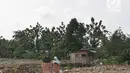 Dua wanita berjalan dekat tumpukan lumpur bercampur sampah dari proyek pengerukan situ Pedongkelan, Cimanggis, Depok, Rabu (28/11). Selain menimbulkan bau, banyaknya lumpur dan sampah membuat lingkungan warga tampak kumuh. (Liputan6.com/Herman Zakharia)