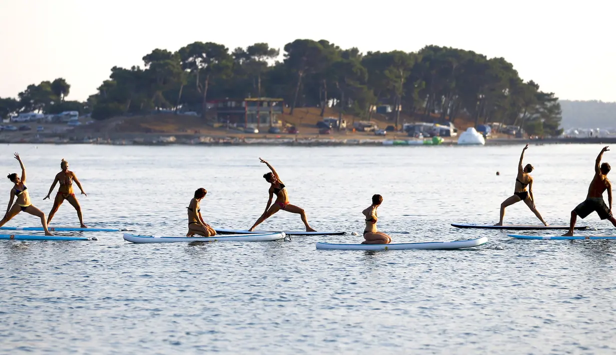 Sejumlah wanita mengenakan bikini saat berlatih yoga Float Metta dengan papan seluncur di Laut Adriatic, Kroasia, Kamis (6/8/2015). (REUTERS/Pawel Kopczynski)
