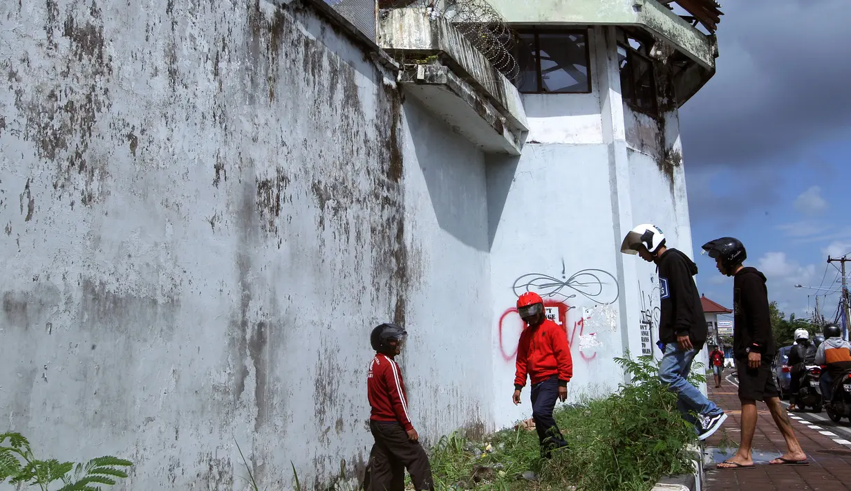 Sejumlah warga mengamati lubang yang digunakan narapidana asing untuk kabur dari Lapas Kerobokan, Bali, Senin (19/6). Empat narapidana asing kabur masih diburu petugas setelah meloloskan diri dari lapas melalui terowongan tersebut. (AP /Firdia Lisnawati)