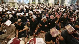 Dalam ritual ini, mereka melakukan ritual dengan menempatkan salinan Alquran di atas kepala mereka. (AP Photo/Hadi Mizban)