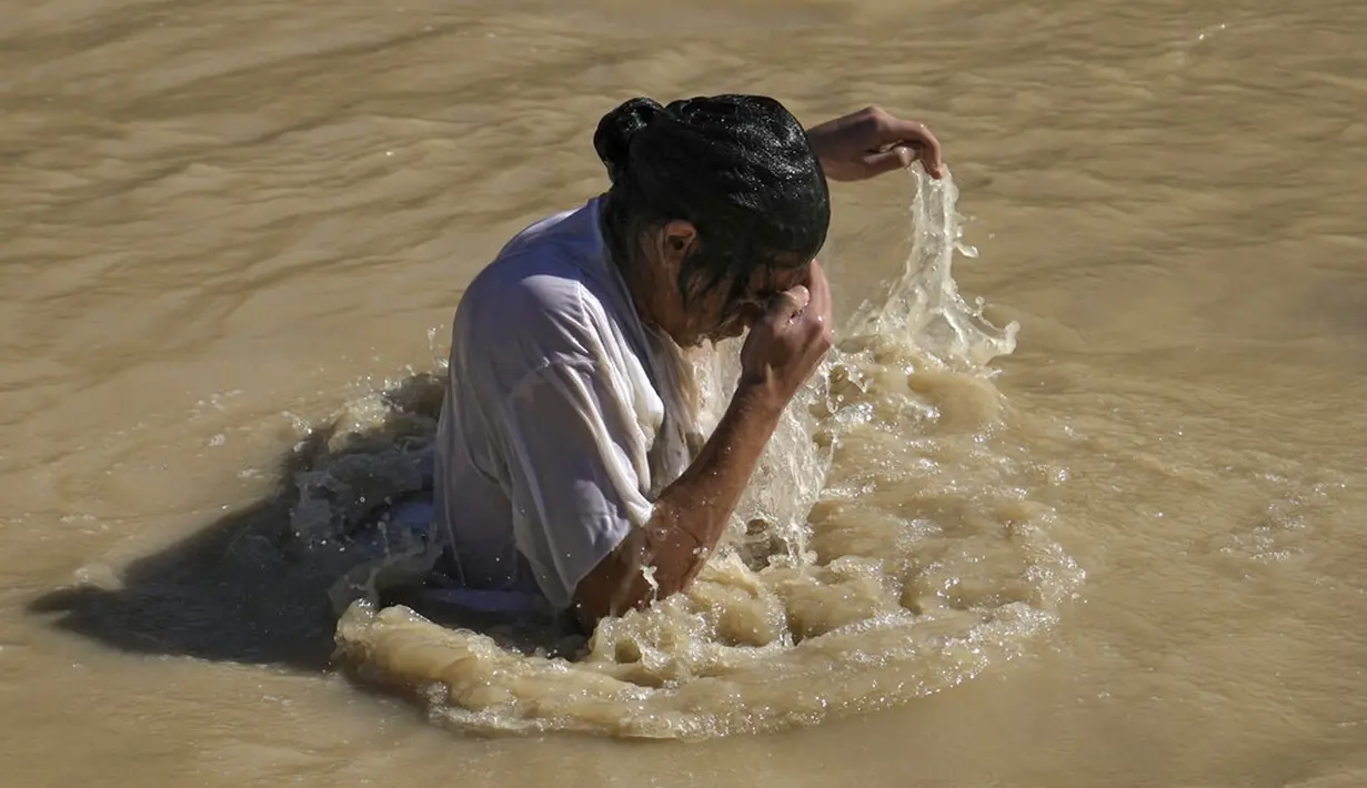 Seorang peziarah Kristen Ortodoks membenamkan dirinya ke Sungai Yordan saat upacara pembaptisan pada perayaan Epiphany di Qasr el Yahud, dekat kota Yerikho, Tepi Barat, 18 Januari 2022. Sungai Yordan dipercaya menjadi tempat di mana Yesus dibaptis. (AP Photo/Mahmoud Illean)