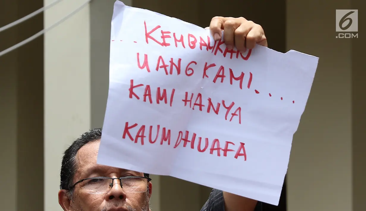 Seorang pria korban dugaan penipuan First Travel menunjukkan menunjukkan poster di Pengadilan Negeri Depok, Jawa Barat, Senin (19/2). Mereka diduga menipu calon jemaah dengan menawarkan perjalanan umrah dengan paket murah. (Liputan6.com/Immanuel Antonius)