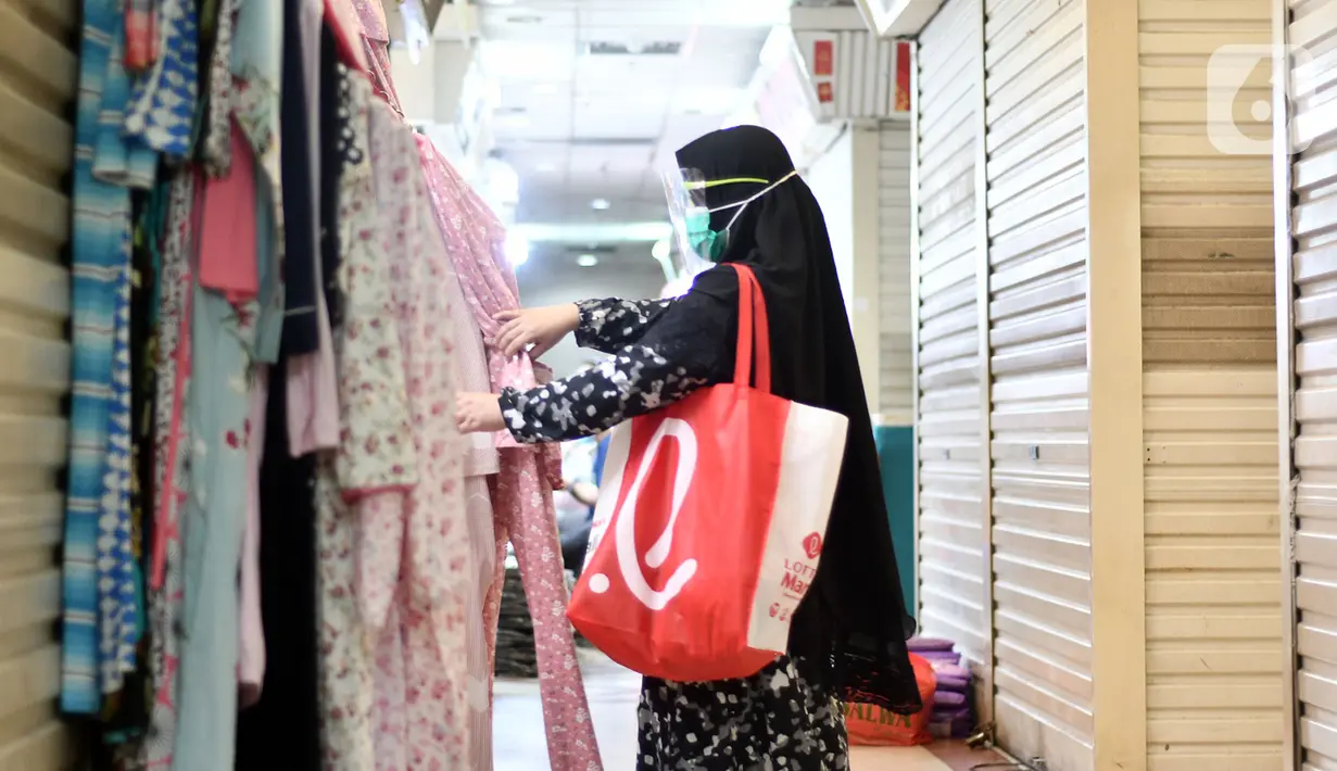 Pengunjung melihat-lihat baju di Pasar Tanah Abang Blok A, Jakarta, Rabu (19/5/2021). Pada hari ini, Pasar Tanah Abang kembali dibuka setelah ditutup sementara selama sepekan pada 12-18 Mei 2021. (Liputan6.com/Herman Zakharia)