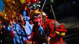 Ekspresi seorang pria yang mengenakan kostum dan topeng kera saat perayaan menjelang tahun baru China di Lisbon, Portugal (21/1).  Pada tahun baru imlek 2017 ini memasuki tahun Ayam Jantan. (AFP/Patricia De Melo Moreira)
