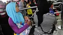 Seorang balita tampak tertidur digendongan ibunya di Stasiun Pasar Senen, Jakarta, Jumat (1/8/14). (Liputan6.com/Faizal Fanani)