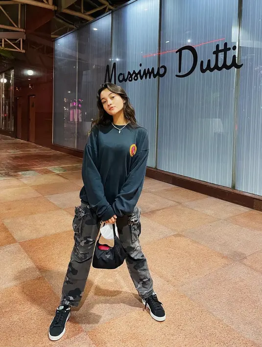 <p>Oversized sweater berwarna hitam dan cargo pants motif army bisa jadi inspirasi hangout bareng teman. Sentuhan warna abu pada celana yang masih memberi nuansa gelap cocok dipadukan dengan sneakers hitam seperti gaya Megan Domani. [Instagram/megandomani1410]</p>