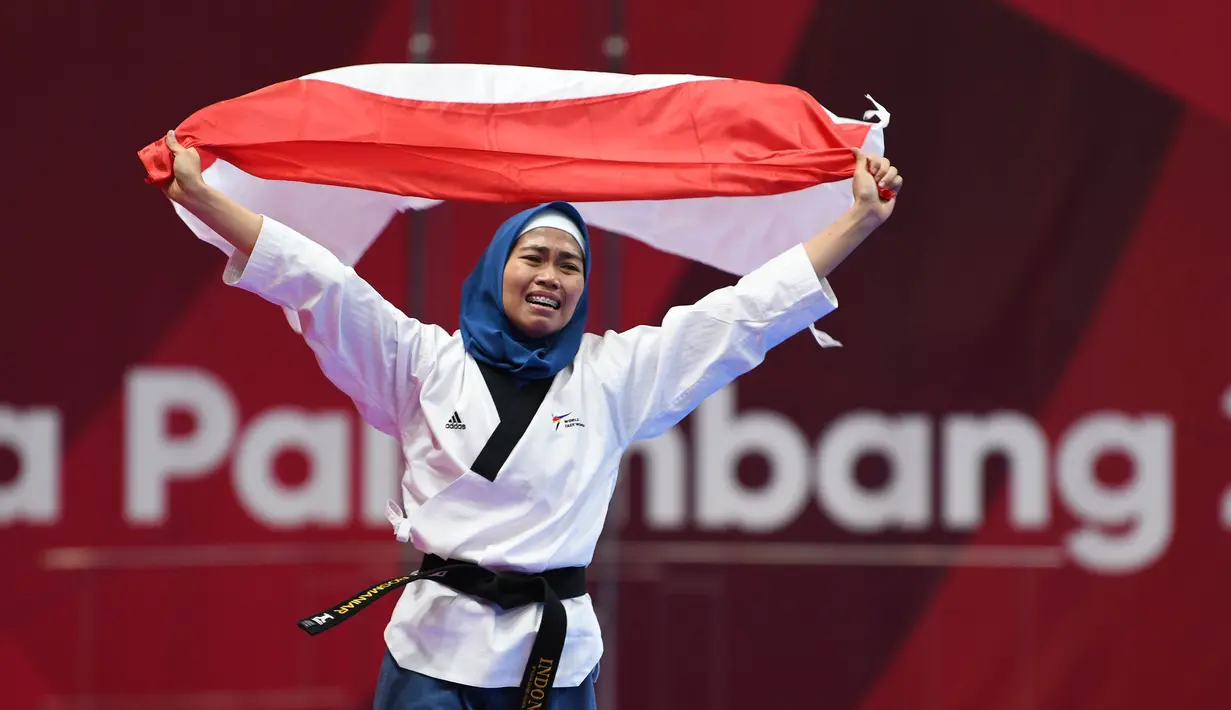 Atlet taekwondo putri Indonesia, Rosmaniar Defia berlari membawa bendera Merah Putih usai mengalahkan Marjan Salahshouri asal Iran pada partai final poomsae individu Asian Games 2018 di Jakarta, Minggu (19/8). (ANTARA FOTO/INASGOC/Darmawan/INP/18)