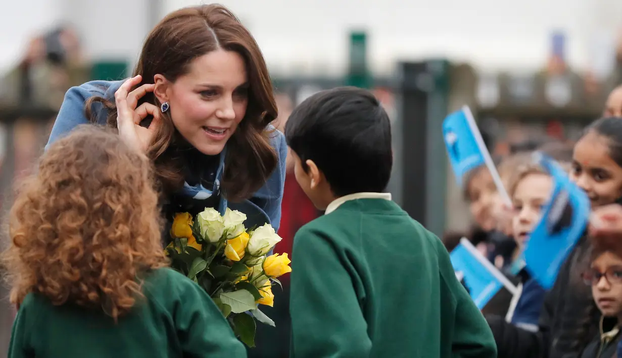 The Duchess of Cambridge, Kate Middleton menerima hadiah bunga dari anak-anak saat berkunjung ke Roe Green Junior School di London, Inggris, Selasa (23/1). (AP Photo/Frank Augstein)