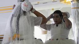 Seorang perempuan Aymara bercermin sebelum tampil di peragaan busana Cholita di El Alto, Bolivia, Rabu (18/5/2022). Memodelkan selimut warna-warni, topi bowler, rok dan perhiasan, di antara busana lainnya, para model yang merupakan penduduk asli tersebut berjalan di atas catwalk untuk mendongkrak perekonomian puluhan perajin dan desainer yang terkena dampak lebih dari dua tahun pembatasan COVID-19. (AP Photo/Juan Karita)