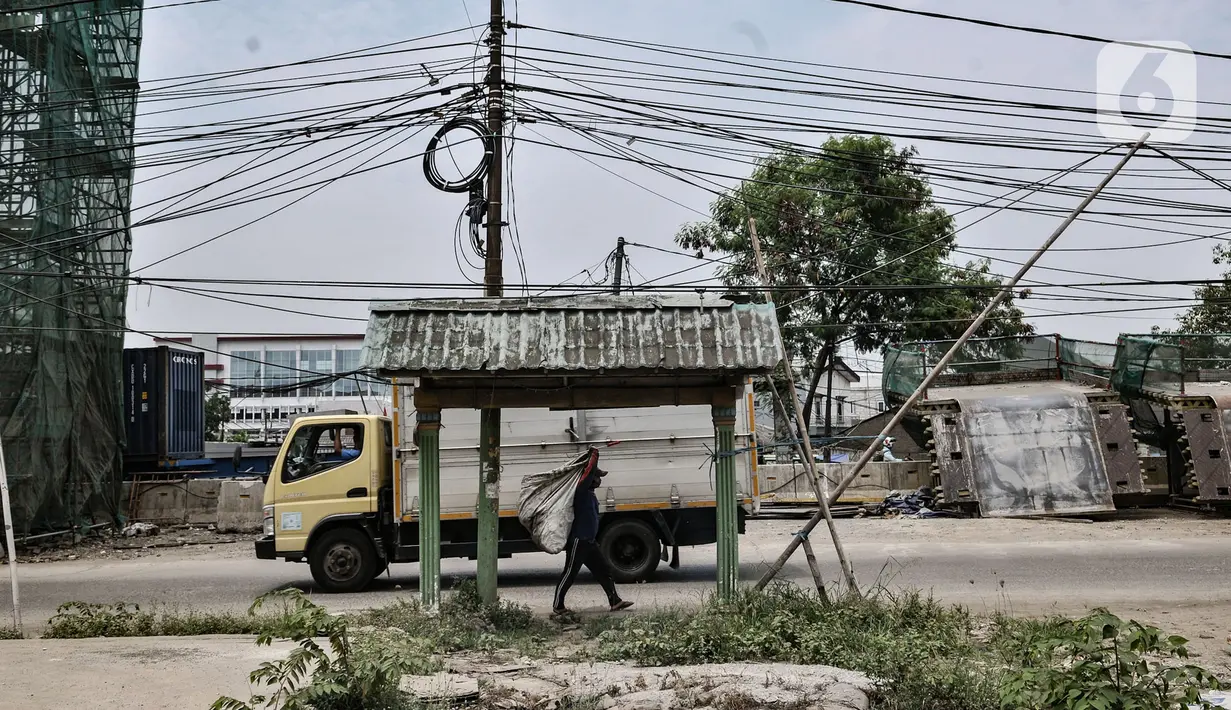Bambu digunakan menyangga instalasi kabel yang semrawut di Jalan Raya Bekasi, Cakung, Jakarta, Rabu (30/9/2020). Minimnya perawatan pascapembebasan lahan permukiman untuk proyek Tol Dalam Kota membuat jaringan kabel listrik di sepanjang jalan tersebut semrawut. (merdeka.com/Iqbal S. Nugroho)