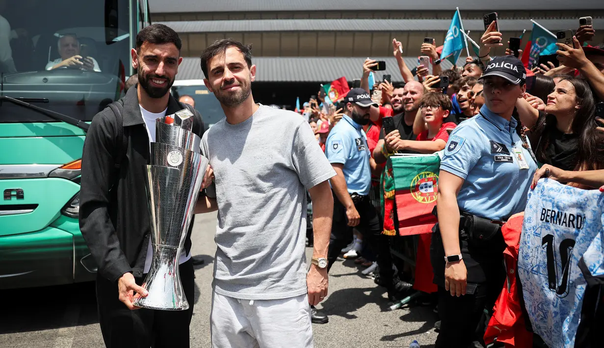 Pemain Timnas Portugal, Bruno Fernandes (kiri) dan Bernardo Silva berfoto bersama dengan fans sambil membawa trofi juara ajang Nations League 2025 setibanya di Bandara Lisbon, Portugal, Senin (09/06/2025) waktu setempat. (AFP/Carlos Costa)