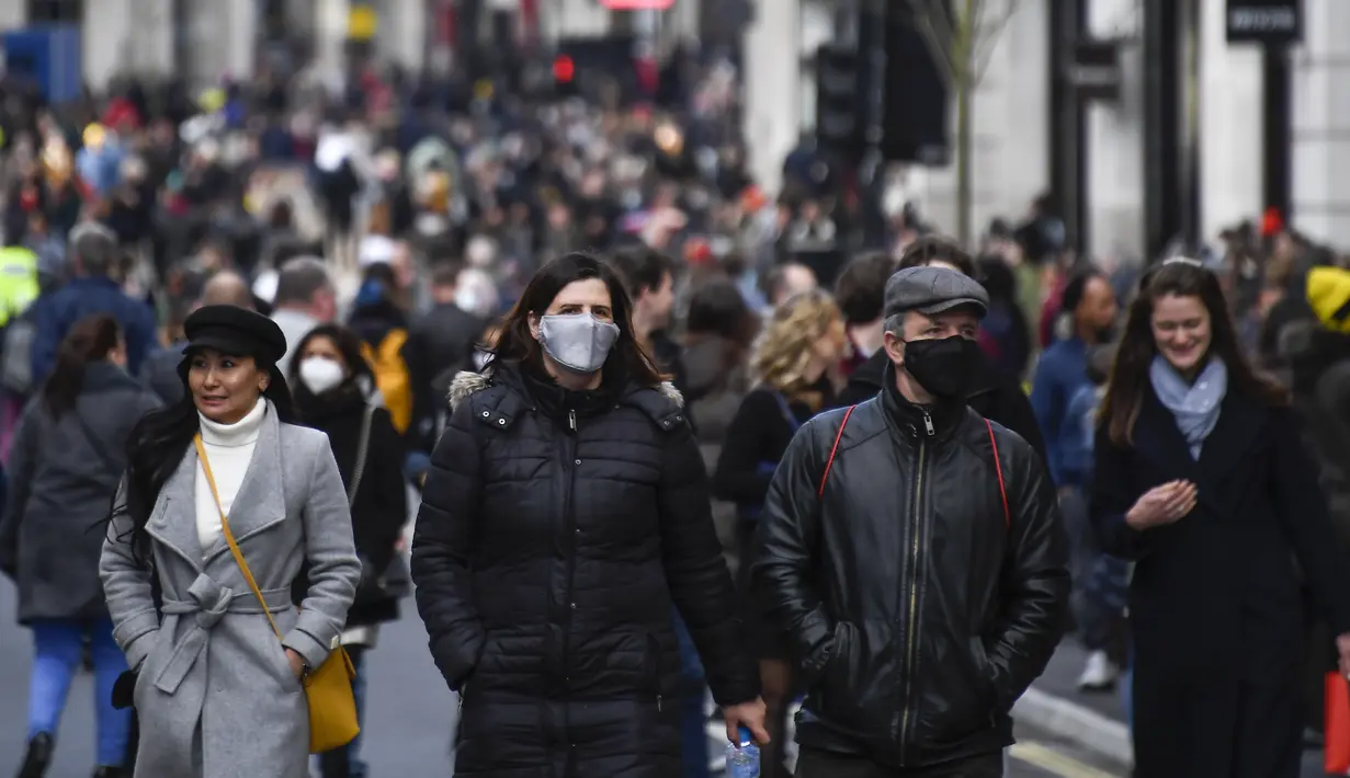 Orang-orang berjalan dengan mengenakan masker dan membawa tas belanjaan di Regent Street, setelah pelonggaran pembatasan virus corona COVID-19 menyusul berakhirnya kebijakan penguncian nasional atau lockdown kedua di Inggris, di London, Sabtu (5/12/2020). (AP Photo/Alberto Pezzali)