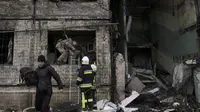 Petugas pemadam kebakaran dan tentara Ukraina mencari warga untuk dievakuasi di sebuah gedung apartemen setelah terkena tembakan artileri di Kyiv, Ukraina (14/3/2022). (AP Photo/Vadim Ghirda)