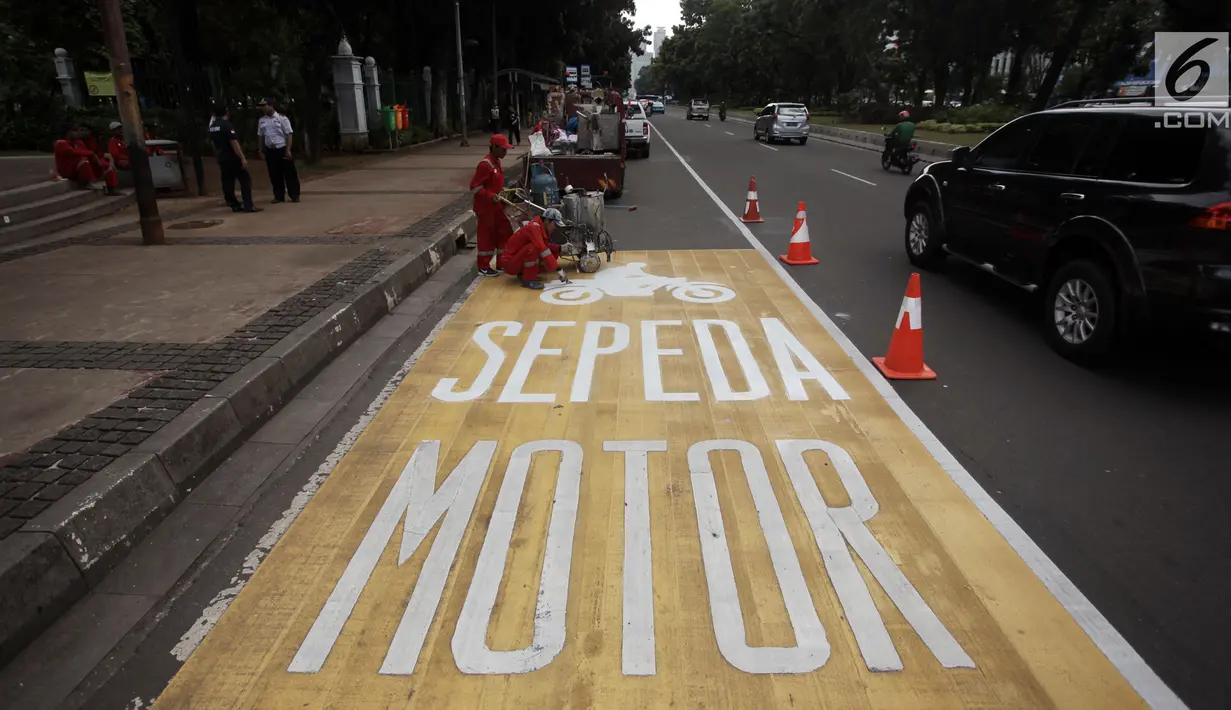 Pekerja menyelesaikan pengecatan rambu jalur kuning khusus sepeda motor di Jalan Medan Merdeka, Jakarta, Selasa (16/1).  Seperti diketahui, Mahkamah Agung (MA) membatalkan pergub larangan sepeda motor melintas di kawasan itu. (Liputan6.com/Arya Manggala)