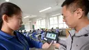 Pengawas mengidentifikasi peserta ujian masuk perguruan tinggi di Handan, Provinsi Hebei, China, (6/6). Pendeteksi sidik jari dan wajah ini dilakukan untuk mencegah adanya praktik joki. (AFP/STR)