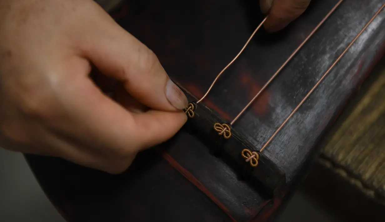 Ma Yuesi (kiri) membuat Guqin, alat musik tradisional China, di kediamannya di Desa Yalan, Distrik Yuhang, Hangzhou, Provinsi Zhejiang, China pada 30 Juni 2020. Selama bertahun-tahun, sebagai pewaris warisan budaya takbenda, Ma tak pernah berhenti meningkatkan keterampilannya. (Xinhua/Weng Xinyang)