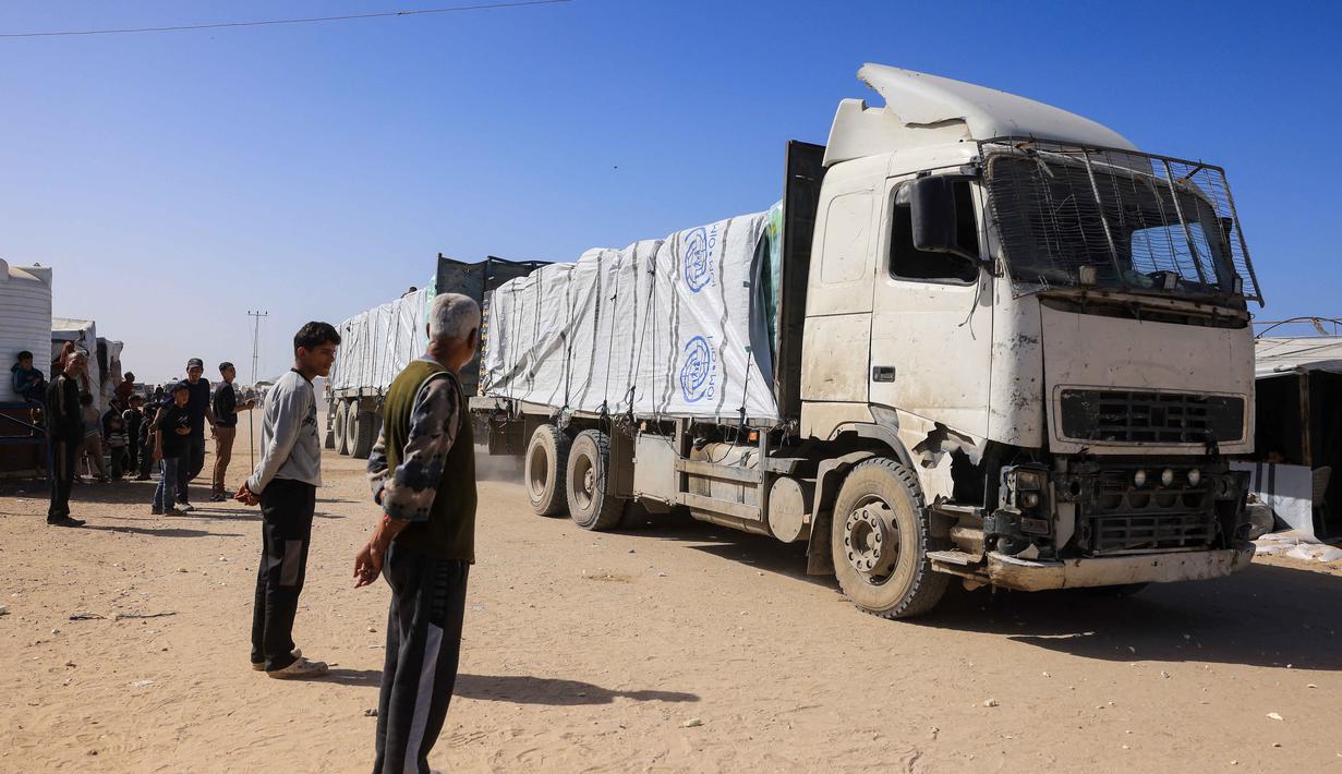 Sebagaimana diketahui, penyeberangan Rafah merupakan gerbang vital bagi warga sipil dan bantuan kemanusiaan. Tampak dalam foto, warga Palestina menyaksikan truk-truk yang membawa bantuan kemanusiaan tiba di Khan Yunis di Jalur Gaza selatan, setelah melewati penyeberangan perbatasan Rafah dari Mesir, pada 1 Februari 2026. (Bashar Taleb/AFP)