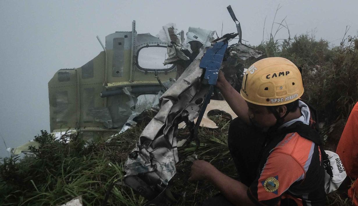 Operasi pencarian dan penyelamatan dilakukan melalui kombinasi jalur udara dan darat dengan mempertimbangkan kondisi cuaca di area pegunungan. Tampak dalam foto, seorang personel pencarian dan penyelamatan membawa puing-puing pesawat turboprop Indonesia Air Transport berjenis ATR 42-500 di Gunung Bulusaraung, Sulawesi Selatan pada Minggu 18 Januari 2026. (Muchtamir Zaide/AFP)