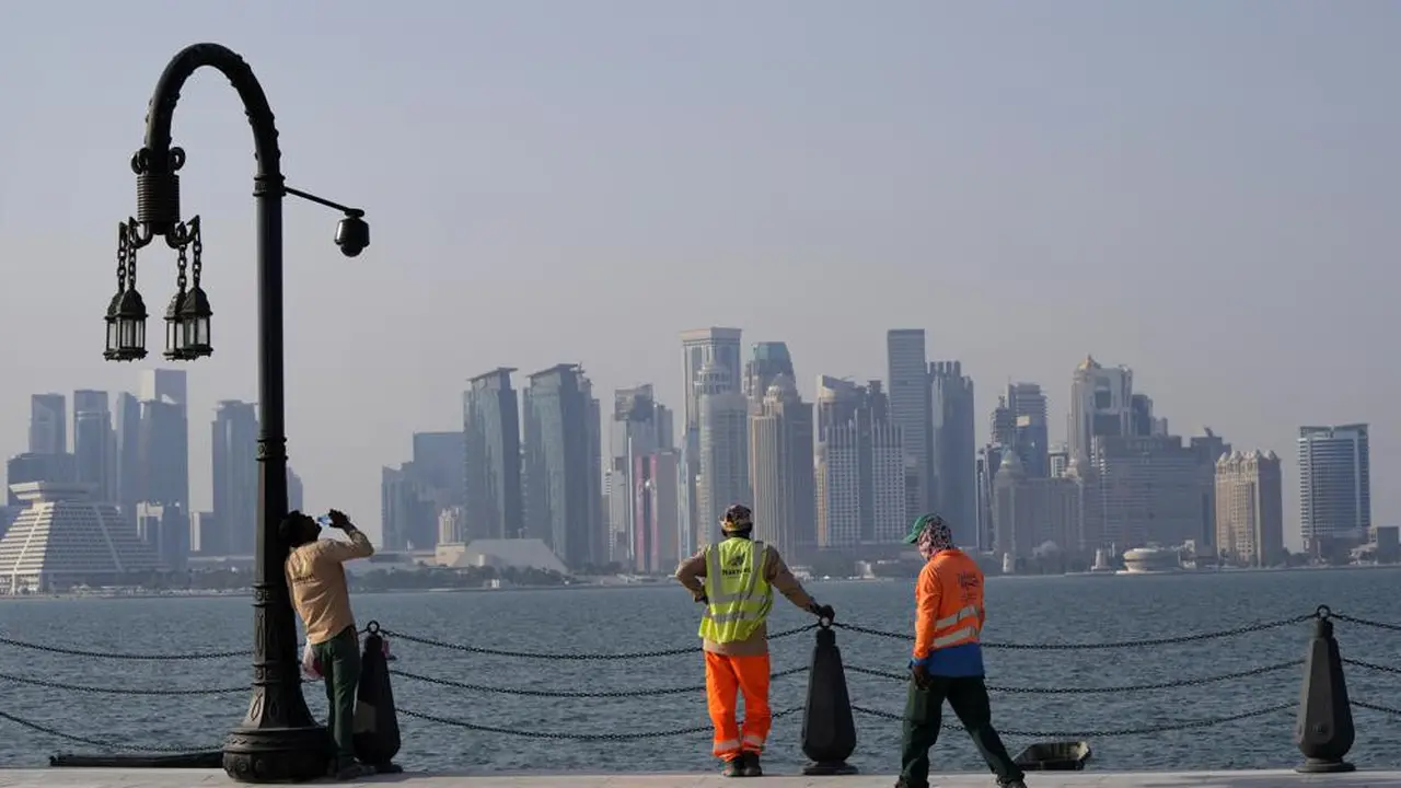 With the city skyline in the background, migrant workers rest at the Doha port, in Doha, Qatar, Sunday, Nov. 13, 2022.