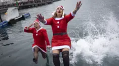 Sejumlah peserta berkostum Sinterklas melompat ke dalam air dalam ajang Copa Nadal yang berlangsung di Barcelona's Port Vell, Barcelona, Kamis (25/12/2025) waktu setempat. Acara tersebut diikuti lebih dari 450 peserta. (AFP/Josep Lago)