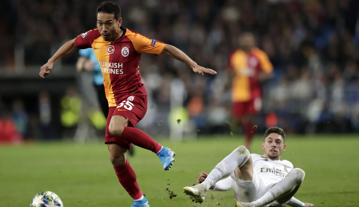Gelandang Real Madrid, Federico Valverde berusaha merebut bola yang dibawa bek Galatasaray, Yuto Nagatomo pada pertandingan Grup A Liga Champions di stadion Santiago Bernabeu, Spanyol (6/11/2019). Madrid menang telak 6-0 atas Galatasaray. (AP Photo/Bernat Armangue)